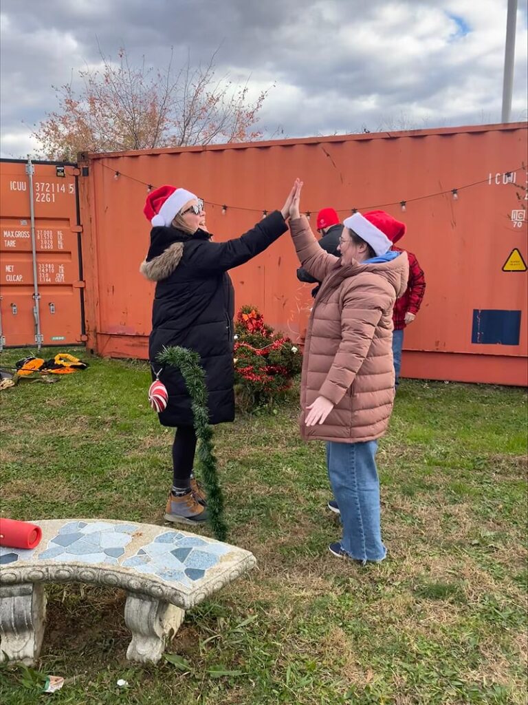 Team members giving each other a high five after wrapping a shepherd hook with garland