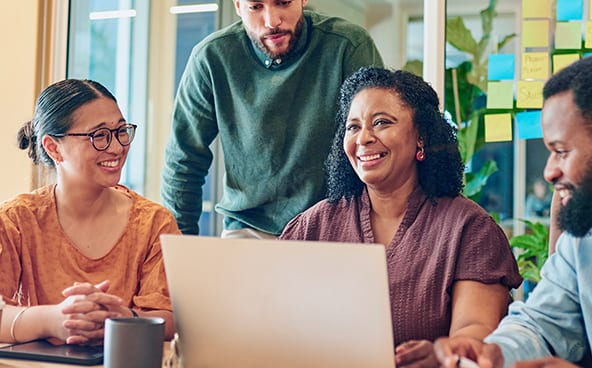 Four people work together around a computer