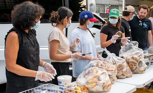 A group of volunteers preparing food to hand out on a busy, city street